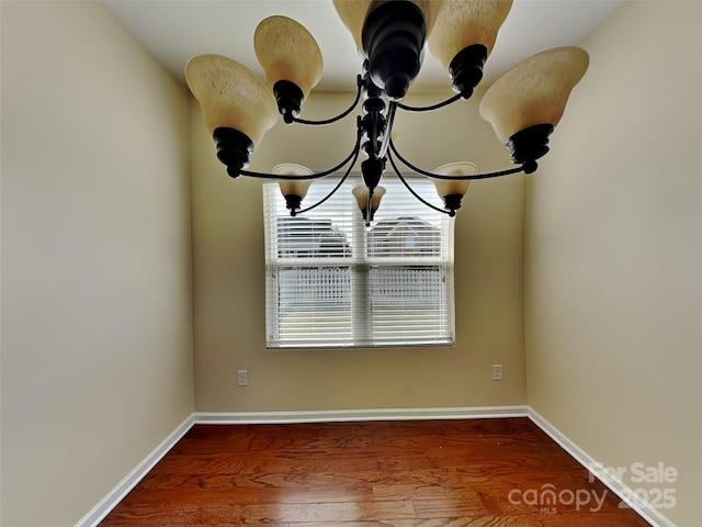 details featuring a chandelier, baseboards, and wood finished floors