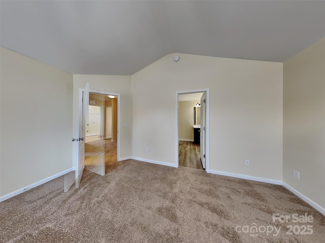 unfurnished bedroom featuring baseboards, carpet flooring, and vaulted ceiling