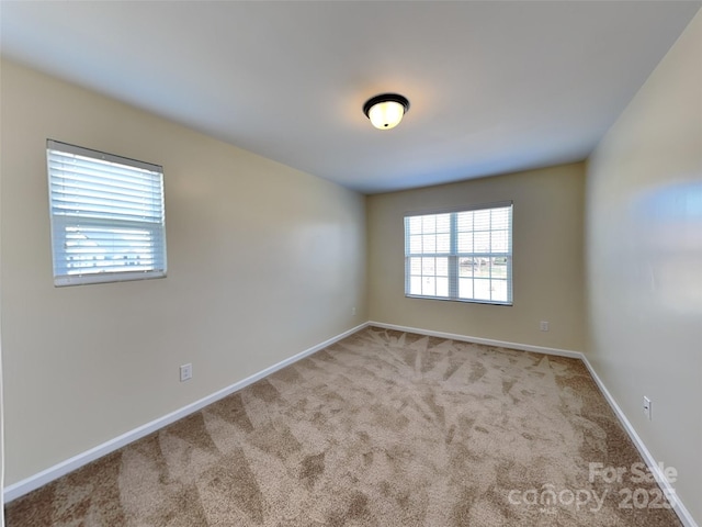 empty room featuring carpet and baseboards