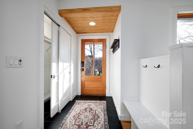 doorway to outside with plenty of natural light, wooden ceiling, and dark tile patterned flooring