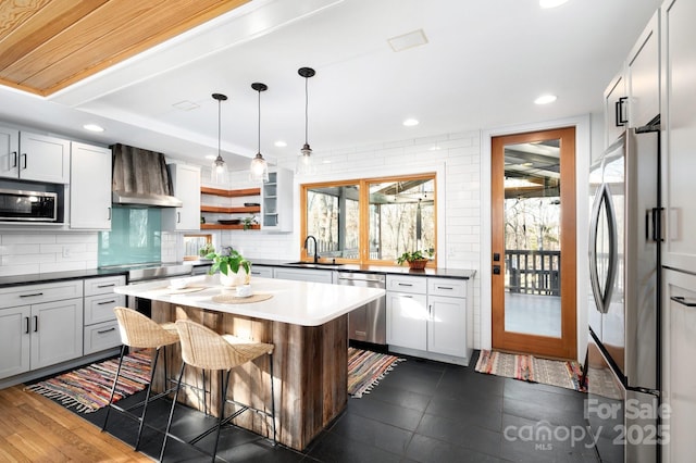 kitchen featuring dark countertops, backsplash, appliances with stainless steel finishes, and wall chimney exhaust hood