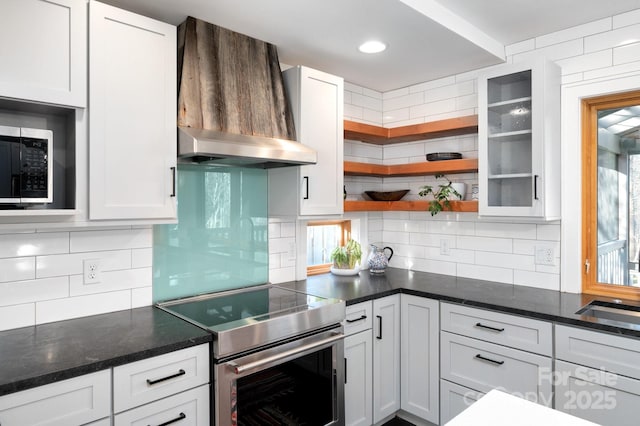 kitchen with white cabinetry, open shelves, wall chimney range hood, and stainless steel appliances