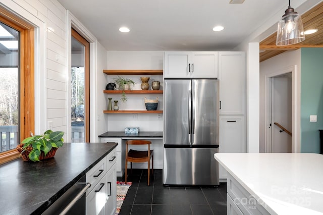 kitchen with dark countertops, dark tile patterned floors, white cabinets, stainless steel fridge, and open shelves