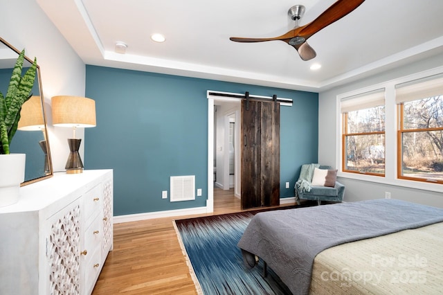 bedroom featuring visible vents, recessed lighting, a barn door, light wood finished floors, and baseboards