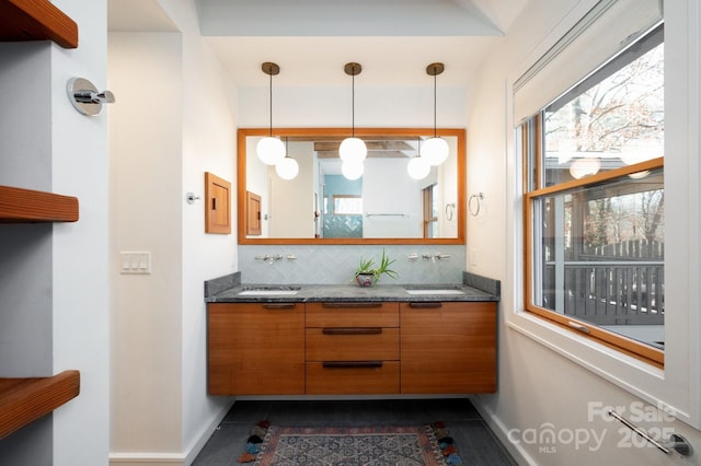 bathroom with decorative backsplash, double vanity, a healthy amount of sunlight, and a sink