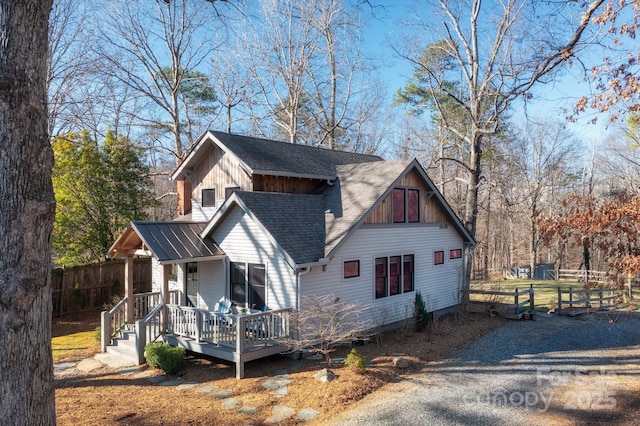 view of side of property featuring a wooden deck, a shingled roof, and fence