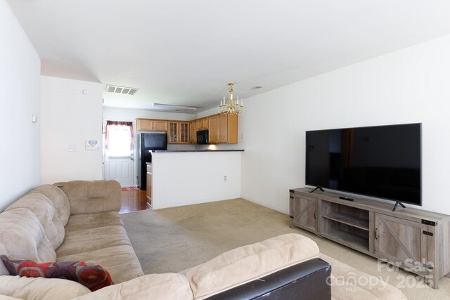 living room with light carpet, visible vents, and a notable chandelier