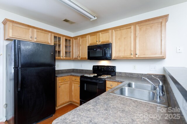 kitchen with wood finished floors, visible vents, a sink, black appliances, and glass insert cabinets