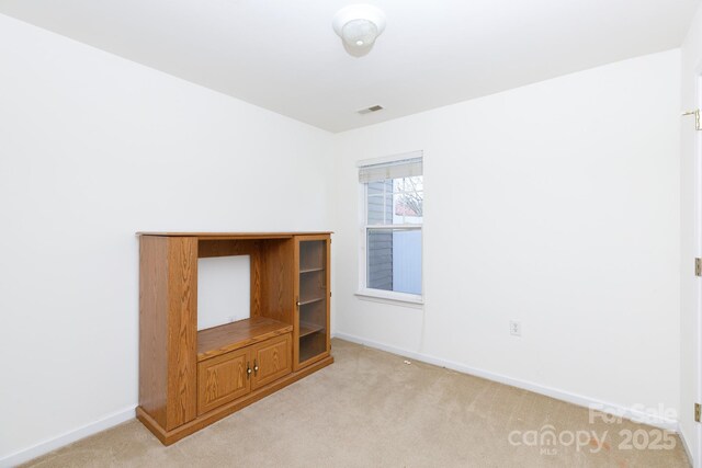 empty room featuring light carpet and baseboards