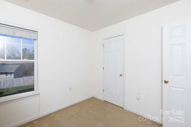 unfurnished room featuring baseboards and light carpet