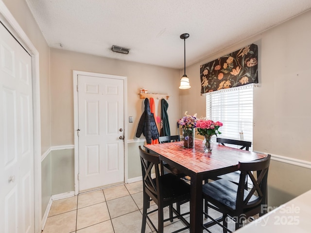 dining space with light tile patterned flooring, baseboards, and a textured ceiling