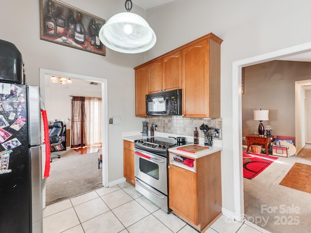 kitchen featuring backsplash, appliances with stainless steel finishes, light countertops, light tile patterned floors, and light colored carpet