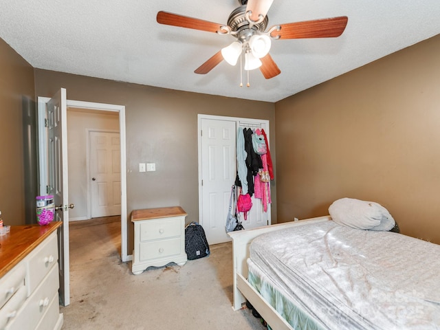 bedroom featuring a closet, light colored carpet, ceiling fan, and a textured ceiling