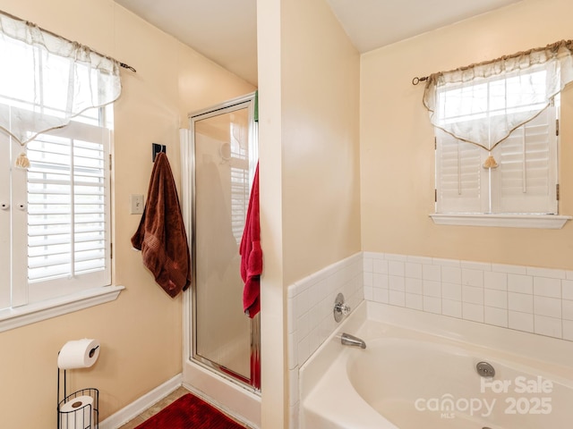 full bath with a bath, a shower stall, and baseboards