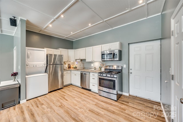 6688 Pine Forest Dr, York, SC 29745 - kitchen featuring appliances with stainless steel finishes, stacked washer / dryer, a sink, white cabinetry, and light wood finished floors