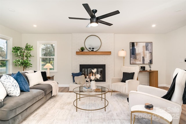 living room with wood finished floors, a brick fireplace, a healthy amount of sunlight, and baseboards