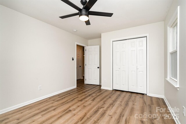 unfurnished bedroom featuring a ceiling fan, wood finished floors, baseboards, and a closet