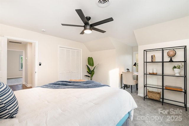 carpeted bedroom with baseboards, visible vents, lofted ceiling, ceiling fan, and a closet