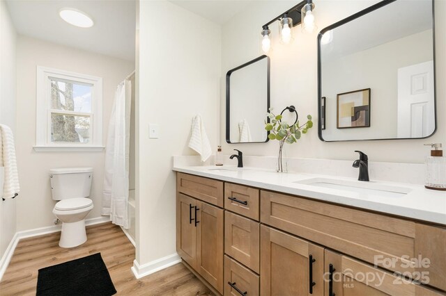 bathroom featuring double vanity, toilet, wood finished floors, and a sink