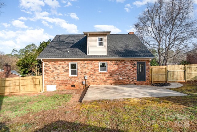 rear view of property featuring fence, a shingled roof, crawl space, brick siding, and a patio area