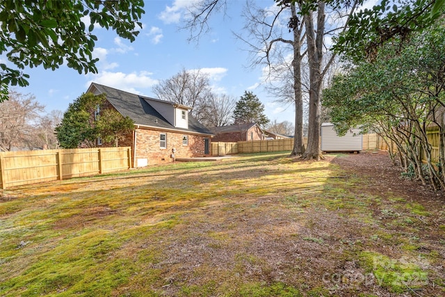 view of yard featuring an outdoor structure, a storage shed, and a fenced backyard