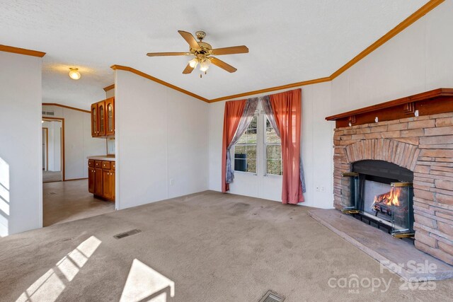 unfurnished living room featuring visible vents, carpet floors, a fireplace, and crown molding