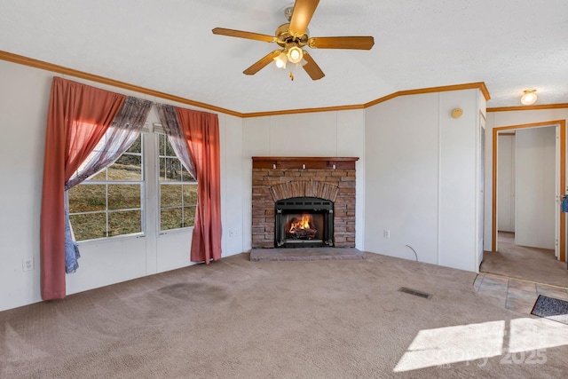 unfurnished living room with visible vents, ornamental molding, a warm lit fireplace, carpet, and ceiling fan