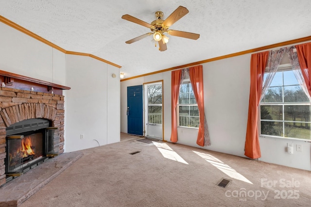 unfurnished living room featuring visible vents, a textured ceiling, carpet floors, a fireplace, and crown molding