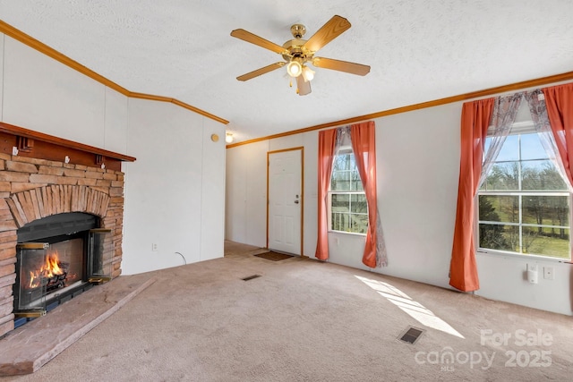 unfurnished living room with a stone fireplace, carpet flooring, visible vents, and ornamental molding