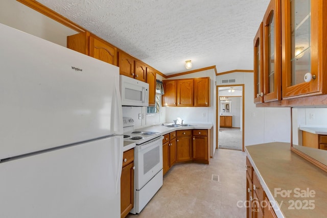 kitchen with glass insert cabinets, vaulted ceiling, brown cabinets, white appliances, and a sink