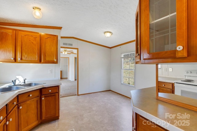 kitchen featuring visible vents, lofted ceiling, a sink, light countertops, and glass insert cabinets