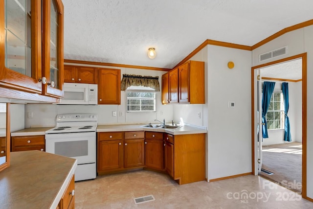 kitchen with a sink, visible vents, white appliances, and brown cabinets