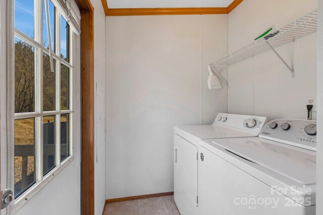 washroom featuring baseboards, separate washer and dryer, and laundry area