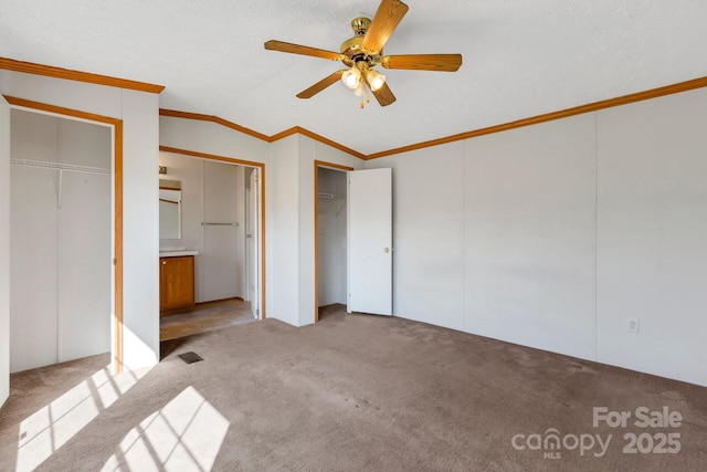 unfurnished bedroom featuring multiple closets, ceiling fan, carpet, lofted ceiling, and ornamental molding