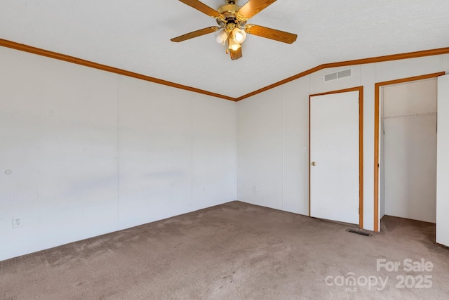 empty room featuring visible vents, ceiling fan, carpet, and lofted ceiling