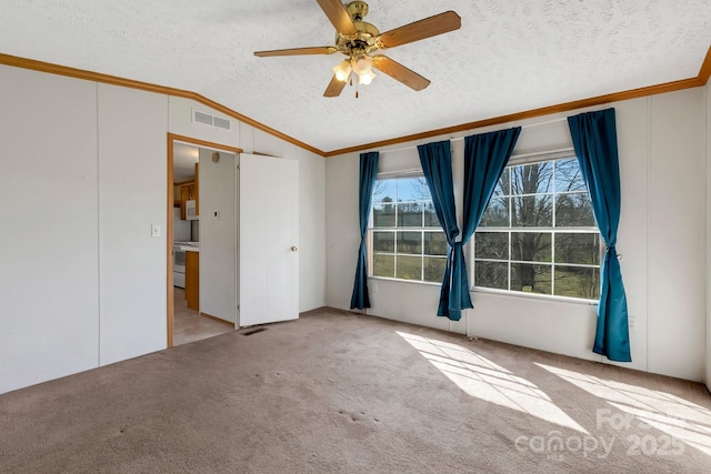 carpeted empty room featuring visible vents, lofted ceiling, a textured ceiling, and crown molding