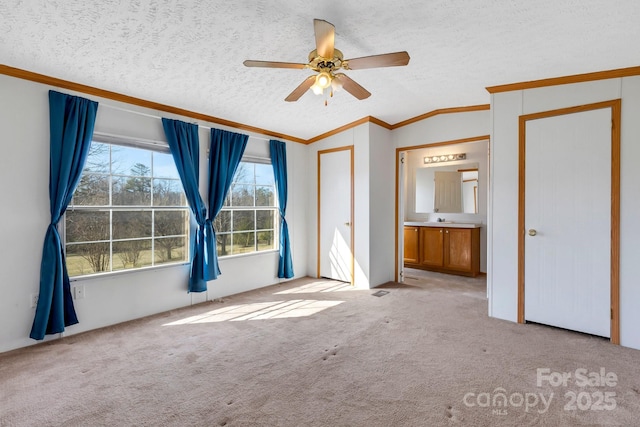 unfurnished bedroom with carpet floors, ornamental molding, vaulted ceiling, a textured ceiling, and a ceiling fan