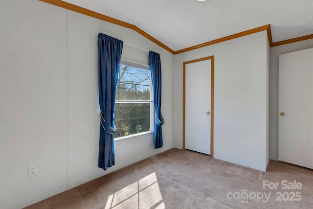 unfurnished bedroom with a textured ceiling, carpet, crown molding, and vaulted ceiling