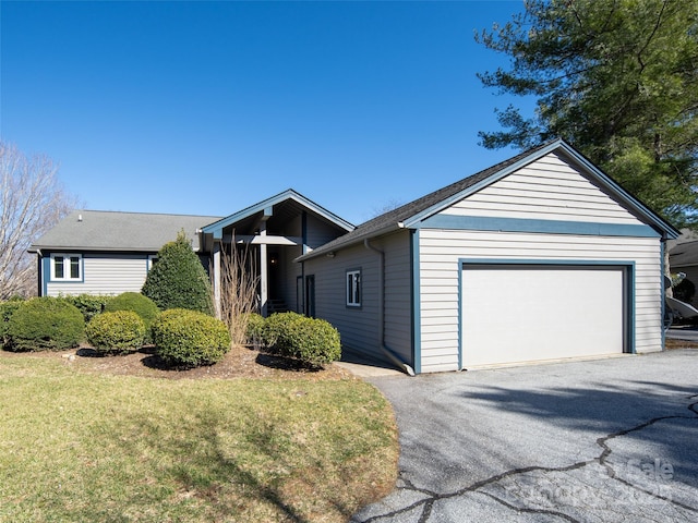 view of front facade featuring aphalt driveway, an attached garage, and a front yard