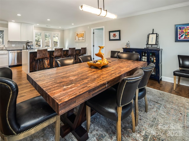 dining area with dark wood-style floors and crown molding