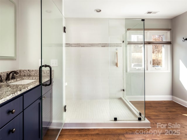 full bath with visible vents, a shower stall, baseboards, wood finished floors, and vanity