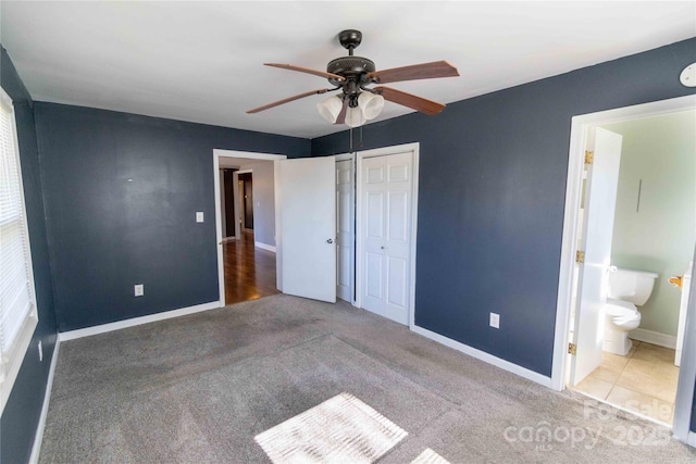 unfurnished bedroom with a closet, carpet floors, baseboards, and ensuite bath