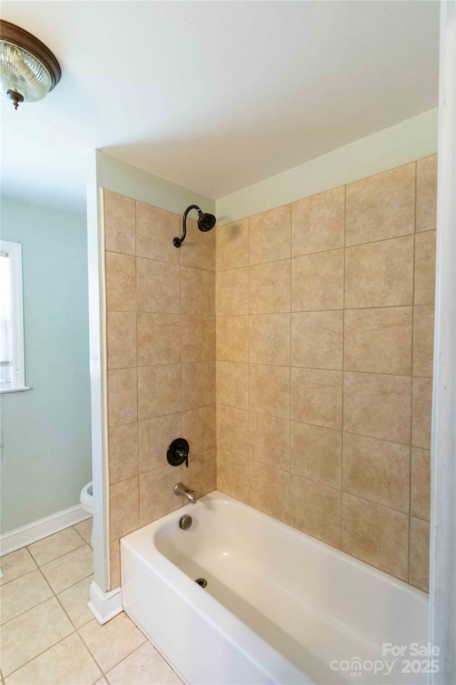 bathroom featuring tile patterned floors, toilet, baseboards, and bathing tub / shower combination