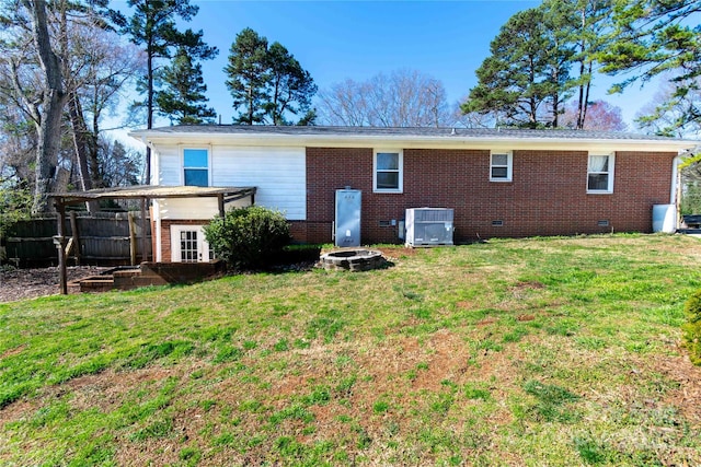 back of house featuring central AC unit, a yard, a fire pit, crawl space, and brick siding