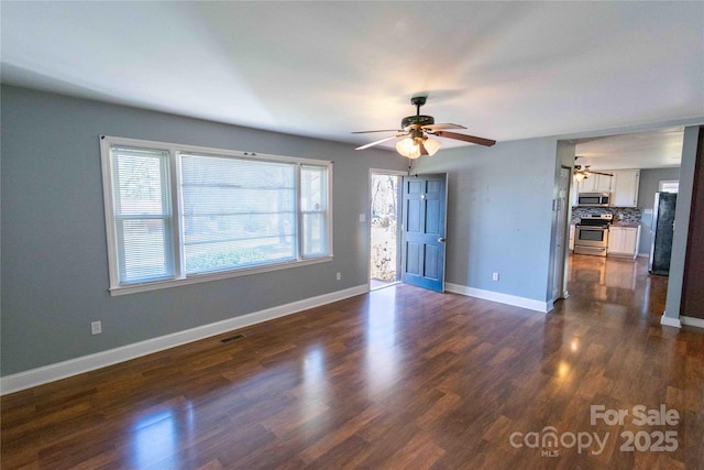 interior space with dark wood-style floors, visible vents, a ceiling fan, and baseboards