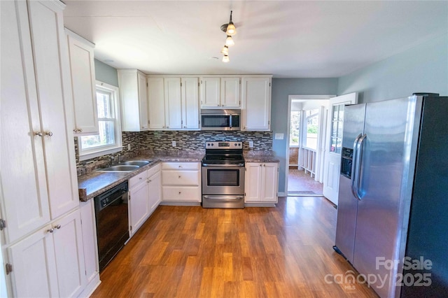 kitchen featuring backsplash, white cabinets, stainless steel appliances, and a sink