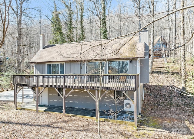 chalet / cabin featuring a wooden deck, board and batten siding, a chimney, and a garage