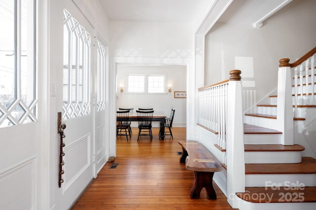 foyer entrance with stairway, visible vents, and hardwood / wood-style flooring