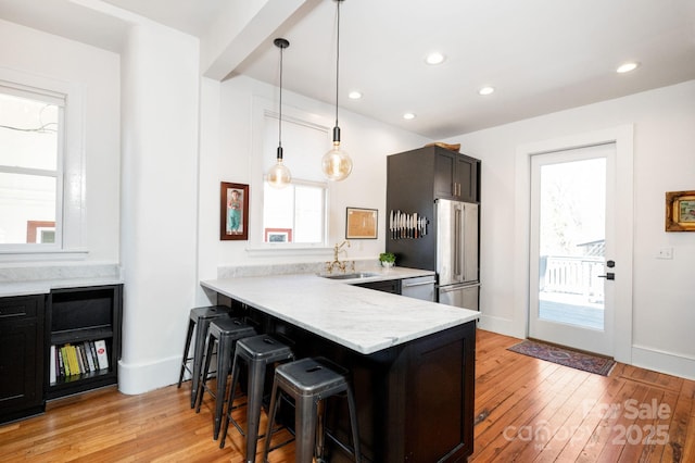 kitchen featuring a sink, stainless steel appliances, a breakfast bar area, and light wood finished floors