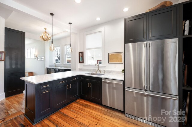 kitchen featuring a sink, light wood-style floors, dark cabinets, and stainless steel appliances